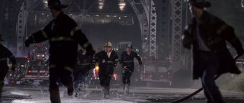 Movie still from “Frequency” (2000), directed by Gregory Hoblit – A group of firemen running in the snow at night; Wide shot, High angle