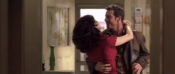 Movie still from “Frequency” (2000), directed by Gregory Hoblit – A man and a woman hugging in a kitchen; Medium shot, Over the shoulder angle