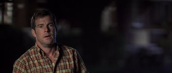 Movie still from “Frequency” (2000), directed by Gregory Hoblit – A man standing in the dark with his head turned to the side; Close Up shot, Over the shoulder angle