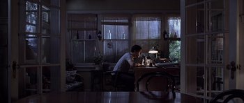Movie still from “Frequency” (2000), directed by Gregory Hoblit – A man sitting at a table in a dark room; Wide shot, Low angle