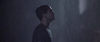 Movie still from “Frequency” (2000), directed by Gregory Hoblit – A man standing in the rain with his head turned to the side; Medium shot, Low angle