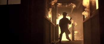 Movie still from “Frequency” (2000), directed by Gregory Hoblit – A fire fighter walking in front of a burning building; Wide shot, Low angle