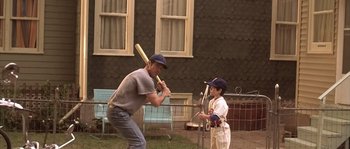Movie still from “Frequency” (2000), directed by Gregory Hoblit – A man and a boy are playing baseball outside; Wide shot, Over the shoulder angle