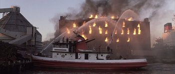 Movie still from “Frequency” (2000), directed by Gregory Hoblit – Firemen are fighting a fire on the side of a building; Extreme Wide shot, Low angle