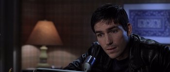 Movie still from “Frequency” (2000), directed by Gregory Hoblit – A young man sitting at a table with a microphone; Close Up shot, High angle