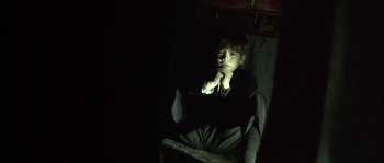 Movie still from “Frequency” (2000), directed by Gregory Hoblit – A young man sitting in a chair in the dark; Medium shot, High angle