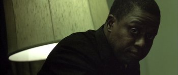 Movie still from “Frequency” (2000), directed by Gregory Hoblit – A man with ear buds sitting in front of a wall; Close Up shot, Low angle