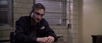 Movie still from “Frequency” (2000), directed by Gregory Hoblit – A man sitting at a table in front of a brick wall; Close Up shot, Over the shoulder angle