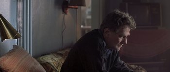 Movie still from “Frequency” (2000), directed by Gregory Hoblit – An older man sitting on a couch in a living room; Close Up shot, Over the shoulder angle