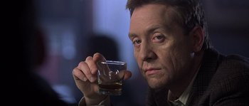 Movie still from “Frequency” (2000), directed by Gregory Hoblit – A person holding a glass of alcohol; Close Up shot, Over the shoulder angle