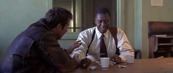 Movie still from “Frequency” (2000), directed by Gregory Hoblit – Two men sitting at a table with a cup of coffee; Medium shot, Over the shoulder angle