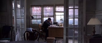 Movie still from “Frequency” (2000), directed by Gregory Hoblit – A man sitting at a computer desk in front of a laptop; Wide shot, High angle