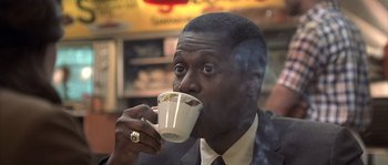 Movie still from “Frequency” (2000), directed by Gregory Hoblit – A person drinking a cup of coffee; Close Up shot, Low angle