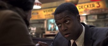 Movie still from “Frequency” (2000), directed by Gregory Hoblit – A man in a suit and tie sitting at a table in a restaurant; Close Up shot, Over the shoulder angle