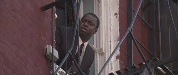 Movie still from “Frequency” (2000), directed by Gregory Hoblit – A man in a suit and tie looking out of a window; Medium shot, Low angle