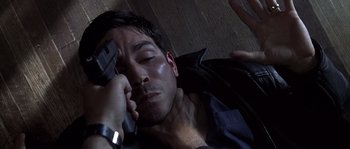 Movie still from “Frequency” (2000), directed by Gregory Hoblit – A man laying on the ground holding a gun in his hand; Close Up shot, Overhead angle