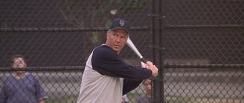 Movie still from “Frequency” (2000), directed by Gregory Hoblit – An older man swinging a baseball bat on a field; Medium shot, Over the shoulder angle