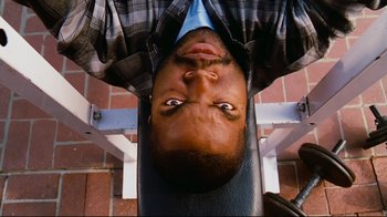 Movie still from “Friday” (1995), directed by F. Gary Gray – A man is laying on a bench with his eyes open; Close Up shot, Overhead angle