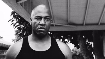 Movie still from “Friday” (1995), directed by F. Gary Gray – A black and white photo of a bald man; Close Up shot, Low angle