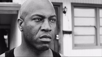 Movie still from “Friday” (1995), directed by F. Gary Gray – A black and white photo of a bald man looking into the camera; Close Up shot, Low angle
