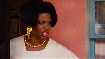 Movie still from “Friday” (1995), directed by F. Gary Gray – A black woman with big hair wearing a white shirt and a gold necklace; Close Up shot, Low angle