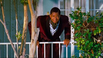 Movie still from “Friday” (1995), directed by F. Gary Gray – A man leaning on a rail in front of a house; Medium shot, Low angle