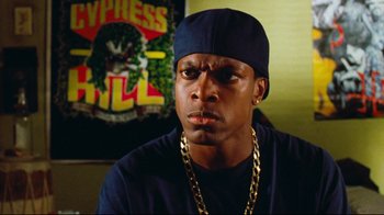 Movie still from “Friday” (1995), directed by F. Gary Gray – A person wearing a hat and chains; Close Up shot, Low angle