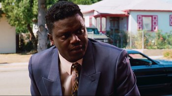 Movie still from “Friday” (1995), directed by F. Gary Gray – A man wearing a suit and tie in front of a house; Close Up shot, Over the shoulder angle