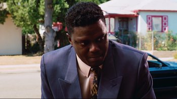 Movie still from “Friday” (1995), directed by F. Gary Gray – A man in a suit and tie looking at the camera; Close Up shot, Low angle