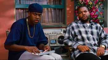 Movie still from “Friday” (1995), directed by F. Gary Gray – A couple of men sitting next to each other on a porch; Medium shot, Low angle