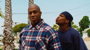 Movie still from “Friday” (1995), directed by F. Gary Gray – Two men standing next to each other on a sunny day; Medium shot, Low angle