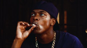 Movie still from “Friday” (1995), directed by F. Gary Gray – A man in a hat is smoking a cigarette; Close Up shot, Low angle