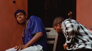 Movie still from “Friday” (1995), directed by F. Gary Gray – Two young men sitting next to each other on a bench; Medium shot, Low angle