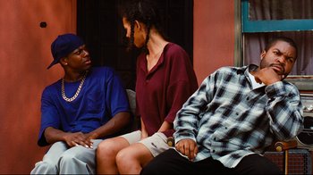 Movie still from “Friday” (1995), directed by F. Gary Gray – A group of people sitting next to each other on a couch; Medium shot, Over the shoulder angle