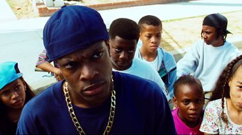Movie still from “Friday” (1995), directed by F. Gary Gray – A group of young men standing next to each other on a street; Close Up shot, Over the shoulder angle