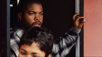 Movie still from “Friday” (1995), directed by F. Gary Gray – A man with a beard is holding a pole; Close Up shot, Over the shoulder angle