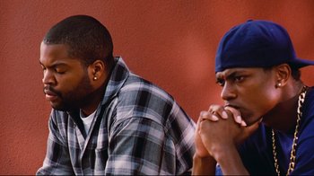 Movie still from “Friday” (1995), directed by F. Gary Gray – Two men sitting next to each other in front of a red wall; Close Up shot, Over the shoulder angle