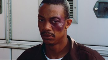 Movie still from “Friday” (1995), directed by F. Gary Gray – A person with a bruise on his face; Close Up shot, Over the shoulder angle