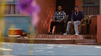 Movie still from “Friday” (1995), directed by F. Gary Gray – Two men sitting on the steps of a house; Wide shot, Low angle