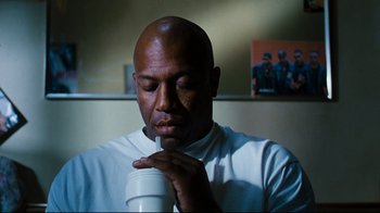 Movie still from “Friday” (1995), directed by F. Gary Gray – A bald man is holding a drink in his hands; Close Up shot, Low angle