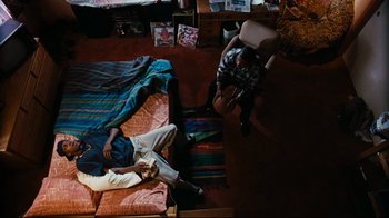 Movie still from “Friday” (1995), directed by F. Gary Gray – Two people laying on a bed in a living room; Wide shot, Overhead angle