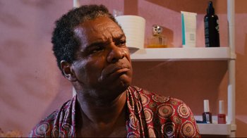 Movie still from “Friday” (1995), directed by F. Gary Gray – An older black man wearing a red and white shirt; Close Up shot, Low angle