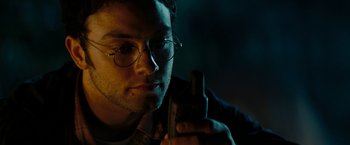 Movie still from “Friday the 13th” (2009), directed by Marcus Nispel – A man with glasses is holding a cell phone; Close Up shot, High angle