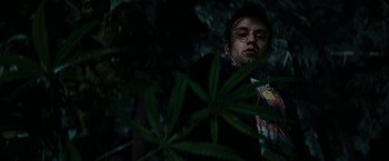 Movie still from “Friday the 13th” (2009), directed by Marcus Nispel – A man with glasses standing next to a plant; Medium shot, Low angle