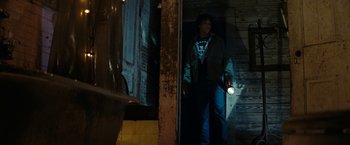 Movie still from “Friday the 13th” (2009), directed by Marcus Nispel – A man standing in a doorway holding a flashlight; Medium shot, Low angle