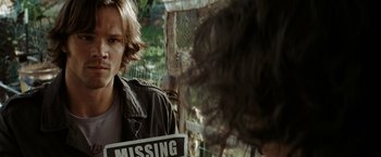 Movie still from “Friday the 13th” (2009), directed by Marcus Nispel – A man holding a missing sign in front of another man; Close Up shot, Over the shoulder angle