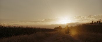 A person riding a horse down a dirt road at sunset