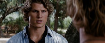 A man with long blonde hair is looking at a woman