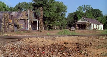 Movie still from “Fried Green Tomatoes” (1991), directed by Jon Avnet – An old abandoned house and car on the side of the road; Extreme Wide shot, High angle