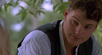 Movie still from “Fried Green Tomatoes” (1991), directed by Jon Avnet – A person wearing a vest near a tree; Close Up shot, Over the shoulder angle
